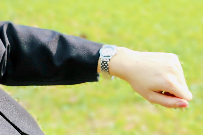 止まってしまった腕時計を眺めるサラリーマン